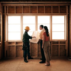 Husband and wife consulting with a architect inside a home under construction.